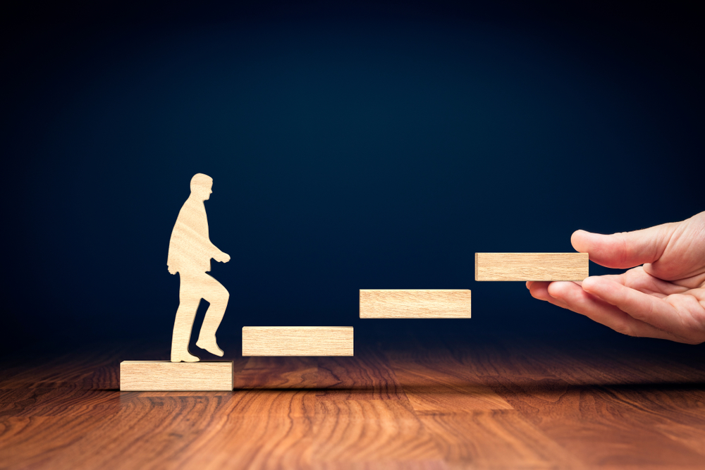 Photo of wooden man walking up wooden steps to illustrate how a typical executive coaching programme with Tim Davies works.